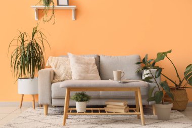 Oturma odasının iç tarafında rahat bir kanepe, bank ve çiçekler var.