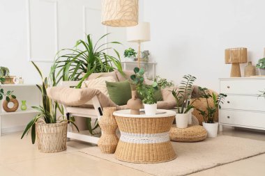 Kanepe, masa ve yeşil bitkilerle aydınlık oturma odasının içinde.