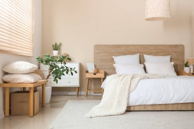 Yastıklı bank, dekoratif ağaç ve yatak odasının içinde rahat bir yatak.