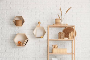 Raflarda kitaplar, mantarlar ve beyaz tuğla duvarın yanında otlar var.