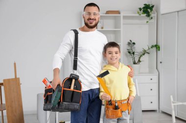 Babası montaj aletleriyle ve oğlu evde.