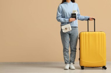 Çantası, pasaportu ve bej duvarın yanında parası olan genç bir kadın.