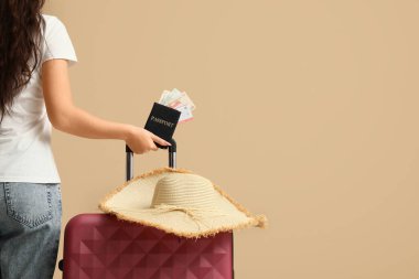 Çantası, pasaportu ve bej rengi geçmişi olan genç bir kadın.