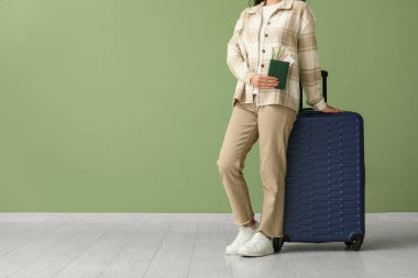 Çantası, pasaportu ve yeşil duvarın yanında parası olan genç bir kadın.