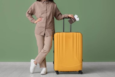 Çantası, pasaportu ve yeşil duvarın yanında biletleri olan genç bir kadın.