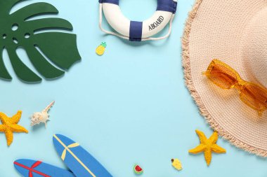 Güneş gözlüğü, can simidi ve mavi arka planda farklı bir plaj dekorundan yapılmış bir şapka çerçevesi.