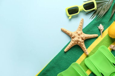 Yüzgeçli plaj havlusu, güneş gözlüğü ve mavi arka planda palmiye yaprağı.