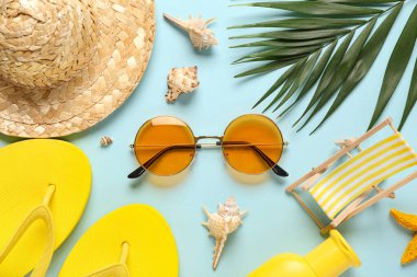 Terlikli şapka, güneş gözlüğü ve mavi arka planda palmiye yaprağı.