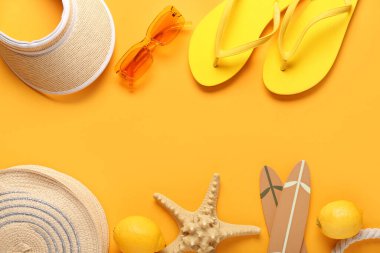 Parmak arası terlikleri, limonları ve turuncu arka planda plaj aksesuarları olan denizyıldızı.