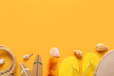 Güneş gözlüklü terlikler ve turuncu arka planda plaj dekoru.