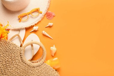 Şapkalı plaj çantası, terlikler ve turuncu arka planda deniz kabukları.