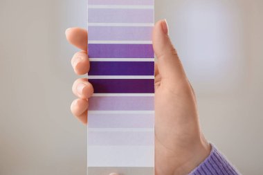 Evde menekşe rengi palet desenli kadın eli, yakın plan.