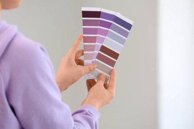 Beyaz duvarda menekşe rengi palet kumaşlı genç bir kadın.