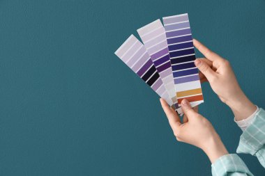 Mor boya paletli kadın elleri koyu turkuaz duvara karşı.