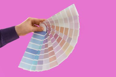 Mor arka planda boya paleti örnekleri olan bir kadın el.