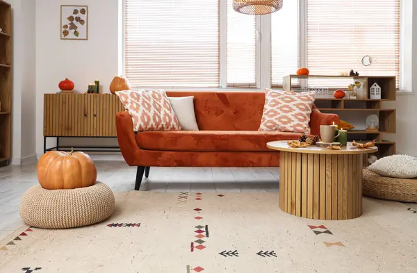 Sonbahar dekoru, kanepesi ve masası olan bir oturma odası.