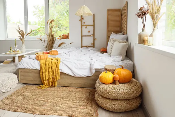 Şık bir yatak odası, rahat bir yatak, sehpa, kanepe ve balkabağı.