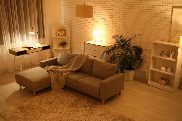 Gece oturma odasının içinde kanepe, raf üniteleri, parlayan lambalar, tuvalet ve işyeri