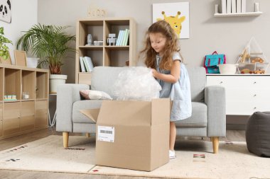 Evde paketleri açan sevimli küçük bir kız.