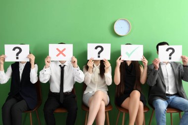 Genç adaylar odada farklı notlarla kağıt çarşaf tutuyorlar.