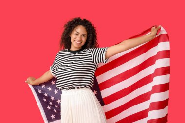 Kırmızı arka planda Amerikan bayrağı olan genç Afro-Amerikalı kadın.