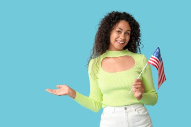 Mavi arka planda bir şey gösteren mutlu Afro-Amerikalı kadın.