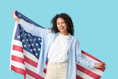 Mavi arka planda Amerikan bayrağı olan mutlu Afro-Amerikan kadın.