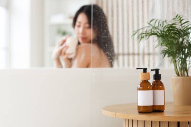 Masada banyo yapan Asyalı genç bir kadına karşı bir şişe duş jeli.