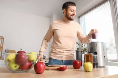 Genç adam mutfakta elma suyu yapıyor.