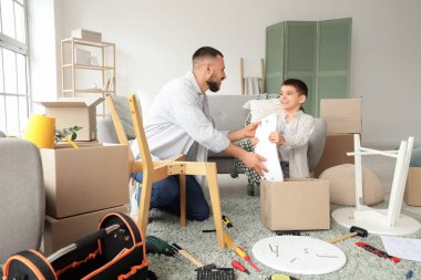 Baba ve oğlu evde mobilya montajı yapıyor.