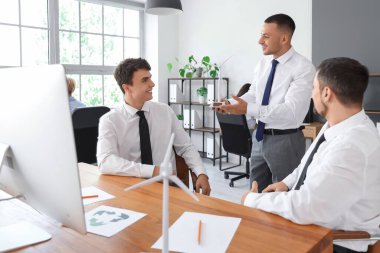 Erkek mühendisler ofiste rüzgar türbini modeliyle çalışıyorlar.