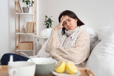 Hasta genç kadın yatak odasında sıcaklığını ölçüyor.