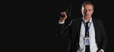 Siyah arka planda silahı olan olgun bir FBI ajanı. Mesaj için yeri var.