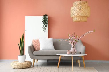 Gri kanepesi ve kahve masasında çiçek açan sakura dalları olan şık bir oturma odası.