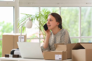 Ofiste cep telefonuyla konuşan paketli genç bir kadın.