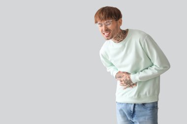 Hafif arka planda karın ağrısı çeken genç bir adam.