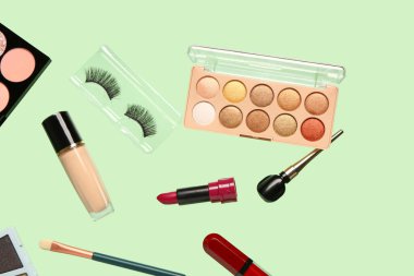 Yeşil arka planda uçan dekoratif kozmetik ürünleri