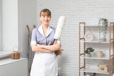 Oturma odasında el temizleyicisiyle gülümseyen hizmetçi.