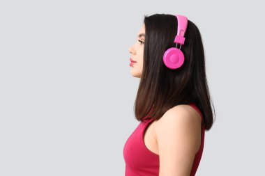 Gri arka planda modern kulaklıklı güzel bir kadın.