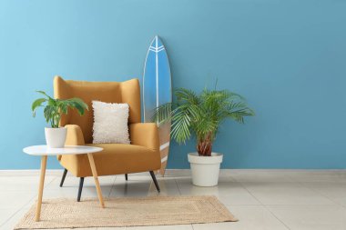 Oturma odasının içinde sörf tahtası, koltuk ve masa var.