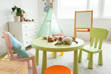 Anaokulunda içinde oyuncaklar, çadır ve beyaz tahta olan bir oyun odası.