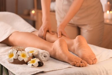 Koyu kaplıcada bacak masajı yaptıran genç bir kadın.