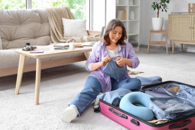 Evde bavul hazırlarken fermuarı çeken genç bir kadın. Seyahat kavramı