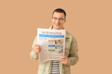 Bej arka planda gazetesi olan yakışıklı genç adam.