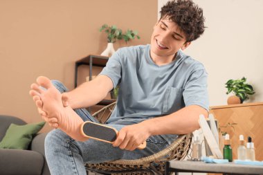 Pedikür yapan, elinde sünger taşıyla yakışıklı genç bir adam.