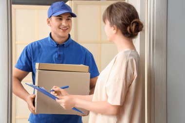 Teslimatçı, kapıdaki kadına bir paket veriyor.