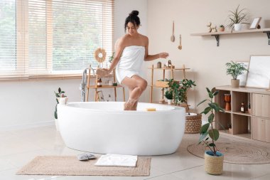 Güzel, genç, mutlu, Afro-Amerikan bir kadın. Evde sünger ve sabun köpüğüyle banyo yapıyor.