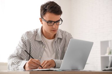 Masada dizüstü bilgisayarla çalışan erkek ekonomist