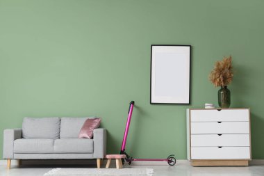 Oturma odasının içinde elektrikli scooter, kanepe ve boş çerçeve.