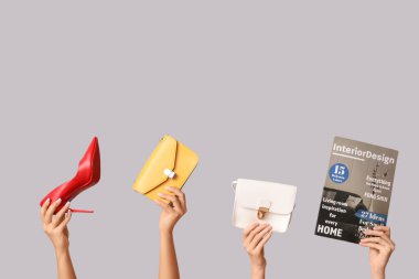 Şarjörlü kadın elleri, yüksek topuklu ve gri arka planda şık çantalar.